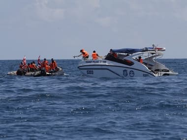 Thai rescue divers and a tourist police boat are seen during a search mission for missing passengers from a capsized tourist boat in the water off Phuket, Thailand, Saturday. AP