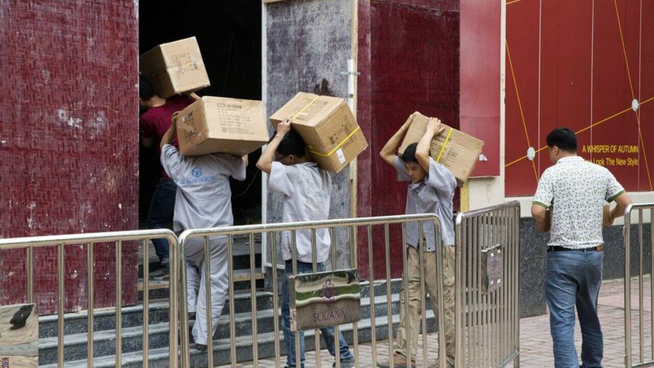 Workers carry boxes of LED lights into a renovation site in Beijing. Image: AP