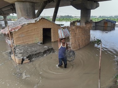 A man shifts from his submerged shanty at Yamuna Khadar after the water level of Yamuna river rises in New Delhi on Sunday. PTI
