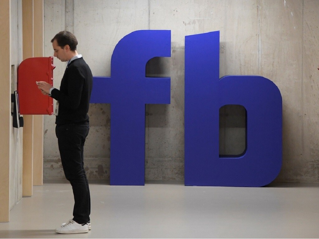 A man waits for an elevator in front of a logo at Facebook's headquarters in London, Britain, December 4, 2017. REUTERS/Toby Melville - RC123AEDCE80