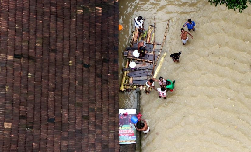 People wait for aid next to makeshift raft at a flooded area. Reuters