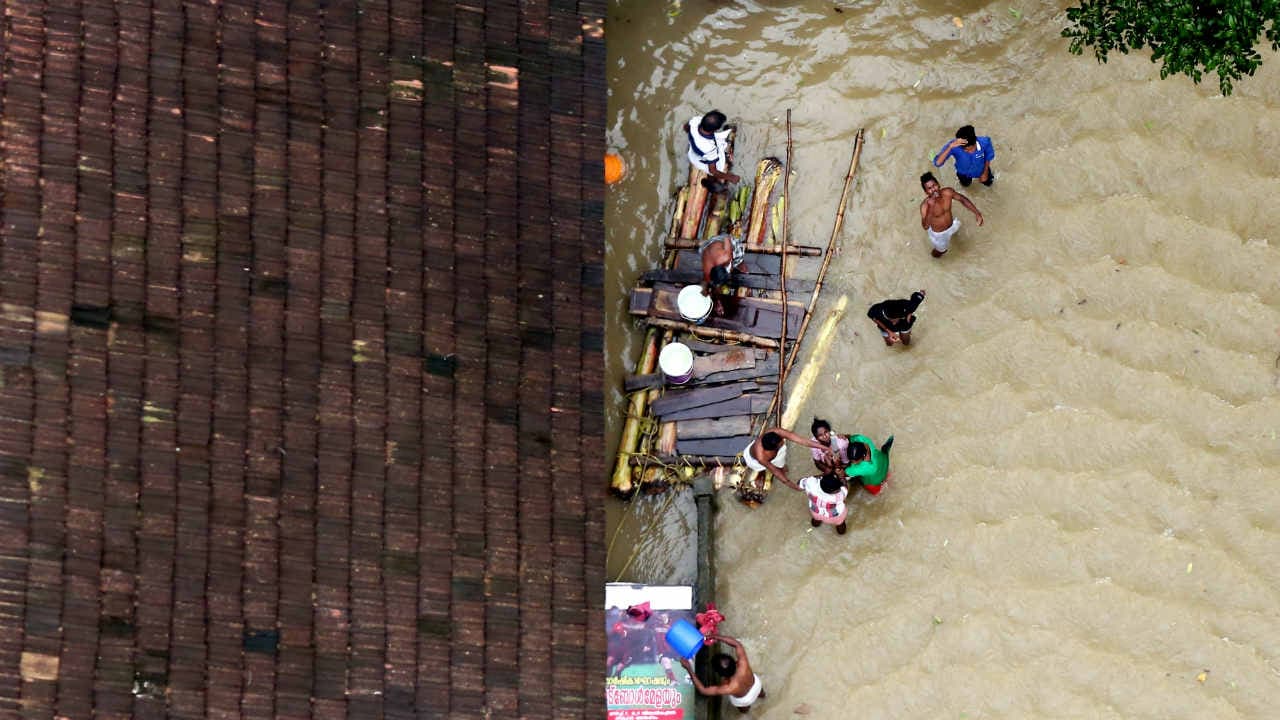 People wait for aid next to makeshift raft at a flooded area in the southern state of Kerala. Image: Reuters