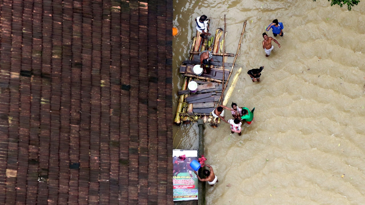 People wait for aid next to makeshift raft at a flooded area in the southern state of Kerala. Image: Reuters