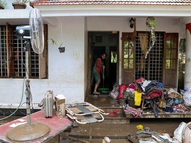 A woman cleans the mud from the entrance of her house following floods in Paravur, Kerala. Reuters