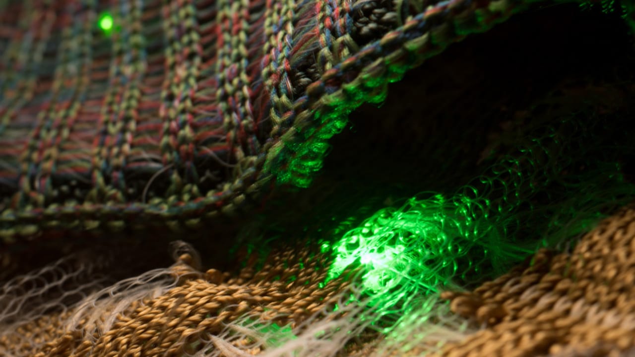 Researchers from MIT have produced fibers embedded with electronics that are flexible enough to weave into wearable clothing, using the new process shows the embedded LEDs turning on and off to demonstrate their functionality. The team has used similar fibers to transmit music to detector fibers, which has been tested even underwater for functionality. Image courtesy: The researchers at MIT