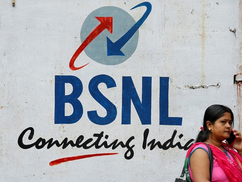 A woman speaks on her mobile phone in front of the logo of Bharat Sanchar Nigam Ltd (BSNL) painted on a wall. Image: Reuters