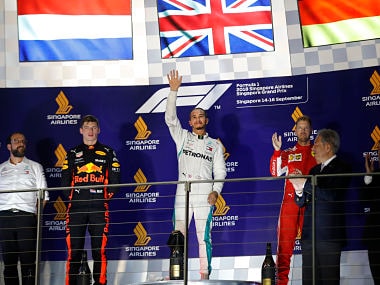 Mercedes driver Lewis Hamilton of Britain, center, waves as he celebrates after winning the Singapore Formula One Grand Prix, next to Red Bull Racing driver Max Verstappen of Netherlands and Ferrari driver Sebastian Vettel of Germany, at the Marina Bay City Circuit in Singapore. AP