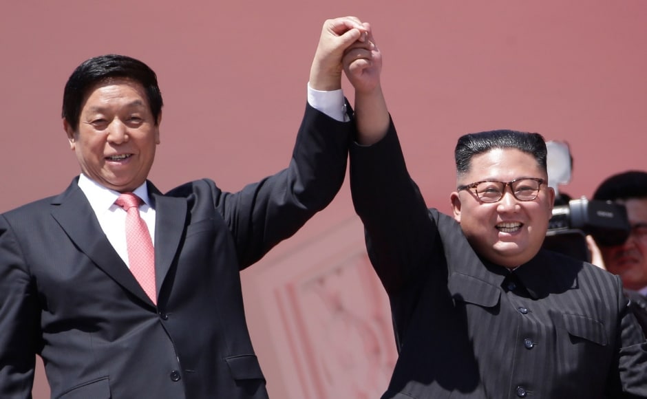 Kim Jong-un at the end of the two-hour event strolled to the edge of the balcony with the Chinese special envoy, Li Zhanshu. The two held up their joined hands to symbolise the countries' traditionally close ties. AP Kim Jong-un at the end of the two-hour event strolled to the edge of the balcony with the Chinese special envoy, Li Zhanshu. The two held up their joined hands to symbolise the countries' traditionally close ties. AP