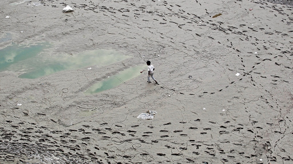 A boy walks along the banks of the river Ganga, in Allahabad — REUTERS