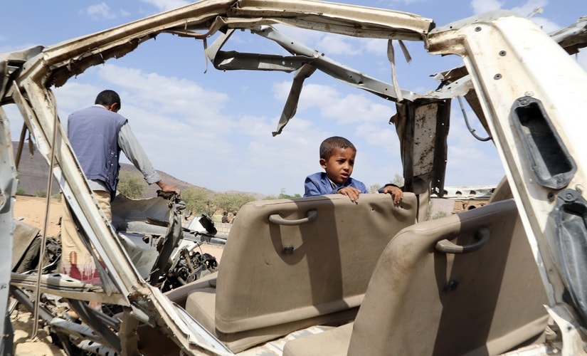 Hafidh Abdullah al-Khawlani, who survived a Saudi-led air strike stands with his father on the wreckage of a bus destroyed by the strike in Saada, Yemen September 4, 2018. His brother was killed by the air strike. Reuters