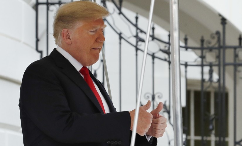 President Donald Trump makes the double thumbs up sign as he leaves the White House. AP