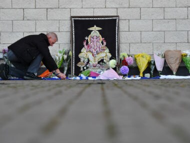 A man adds to flowers and Leicester City scarfs left as tributes outside Leicester City Football Club's King Power Stadium in Leicester. AFP
