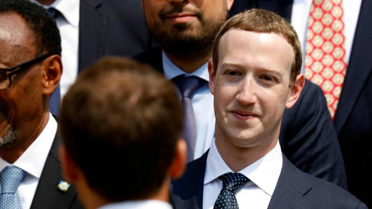 Facebook's CEO Mark Zuckerberg listens to French President Emmanuel Macron after a family picture with guests of the 