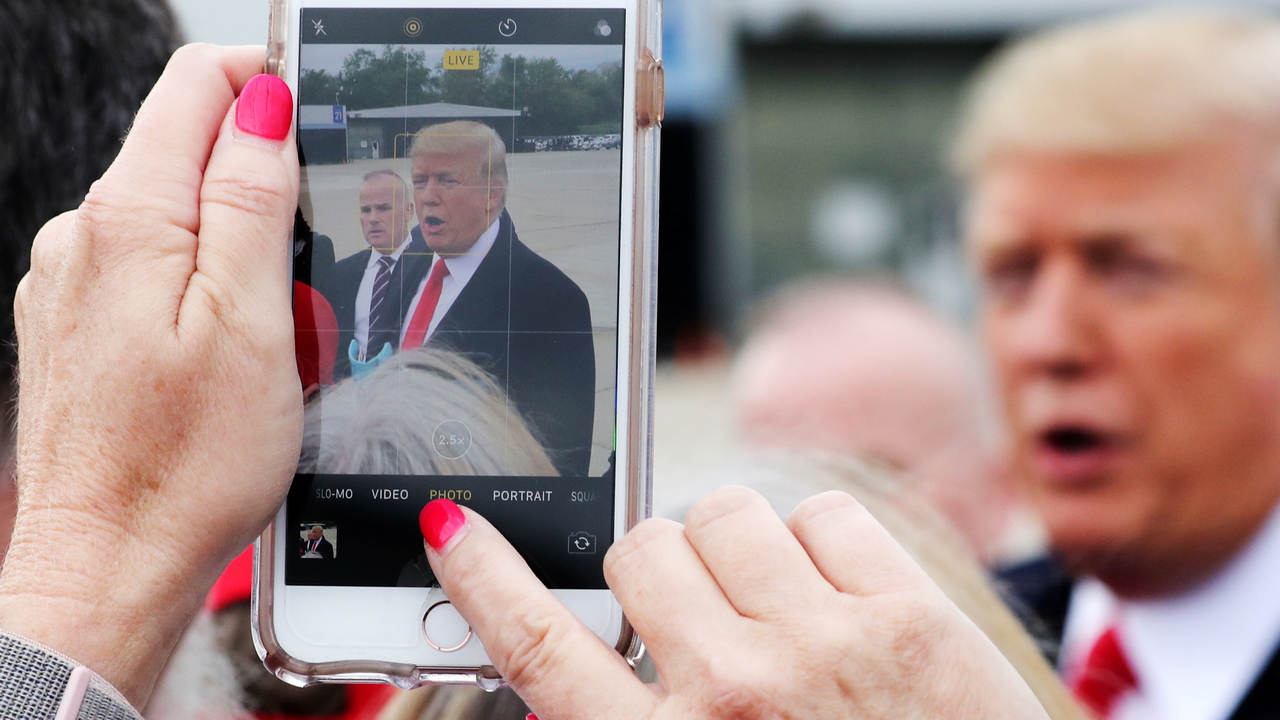 A woman in the crowd on the airport tarmac shoots a mobile phone picture of U.S. President Donald Trump at Cincinnati Municipal Lunken Airport as he arrives for an evening campaign rally in Cincinnati, Ohio, U.S., October 12, 2018. REUTERS/Jonathan Ernst - RC1F9B1F3630
