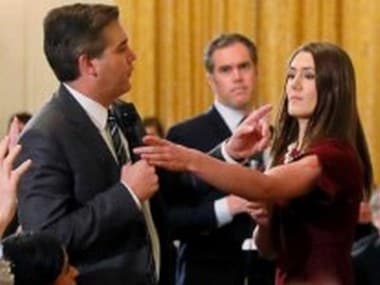 A White House staff member reaches for the microphone held by CNN's Jim Acosta as he questions Donald Trump. Reuters