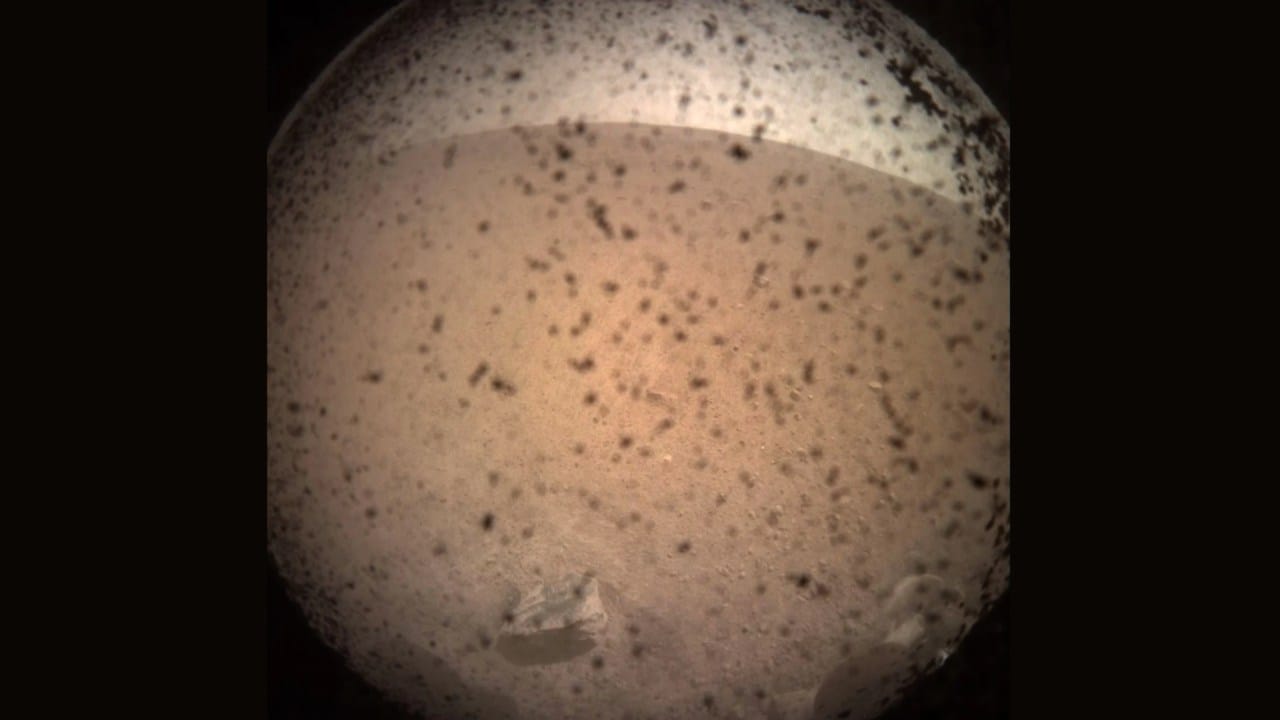 The first image of Mars taken by NASA's InSight Mars lander after its successful landing on the 'aprking lot'-like Elysium Planitia on 26 November, 2018. The dust seen in the image is a dust cover protecting its camera till InSight sends back a signal assuring the team it has landed in a safe spot. Image courtesy: NASA JPL