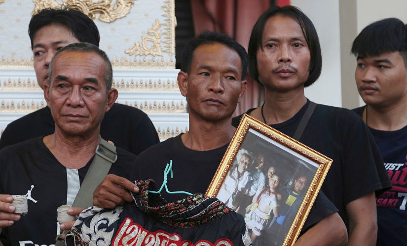 In this Thursday, Nov. 15, 2018, photo, relatives of 13-year-old Thai kickboxer Anucha Tasako hold his boxing shorts and a portrait during his funeral services in Samut Prakan province, Anucha died of a brain hemorrhage two days after he was knocked out in a bout on Nov. 10 that was his 174th match in the career he started at age 8. Thai lawmakers recently suggested barring children younger than 12 from competitive boxing, but boxing enthusiasts strongly oppose the change. (AP Photo/Sakchai Lalit)