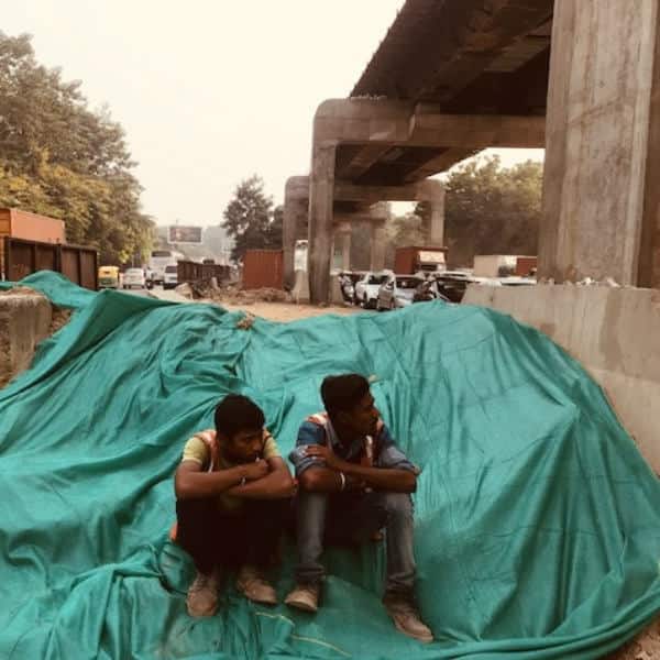 After work was halted on Thursday morning, labourers sitting below an flyover construction site in Vasant Vihar, New Delhi. Pallavi Rebbapragada