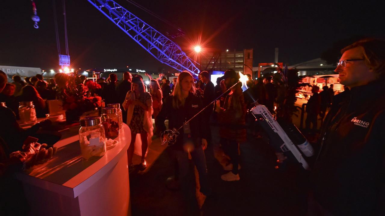 An attendee operates a Boring Company flamethrower to toast a marshmallow during an unveiling event. Image: AP