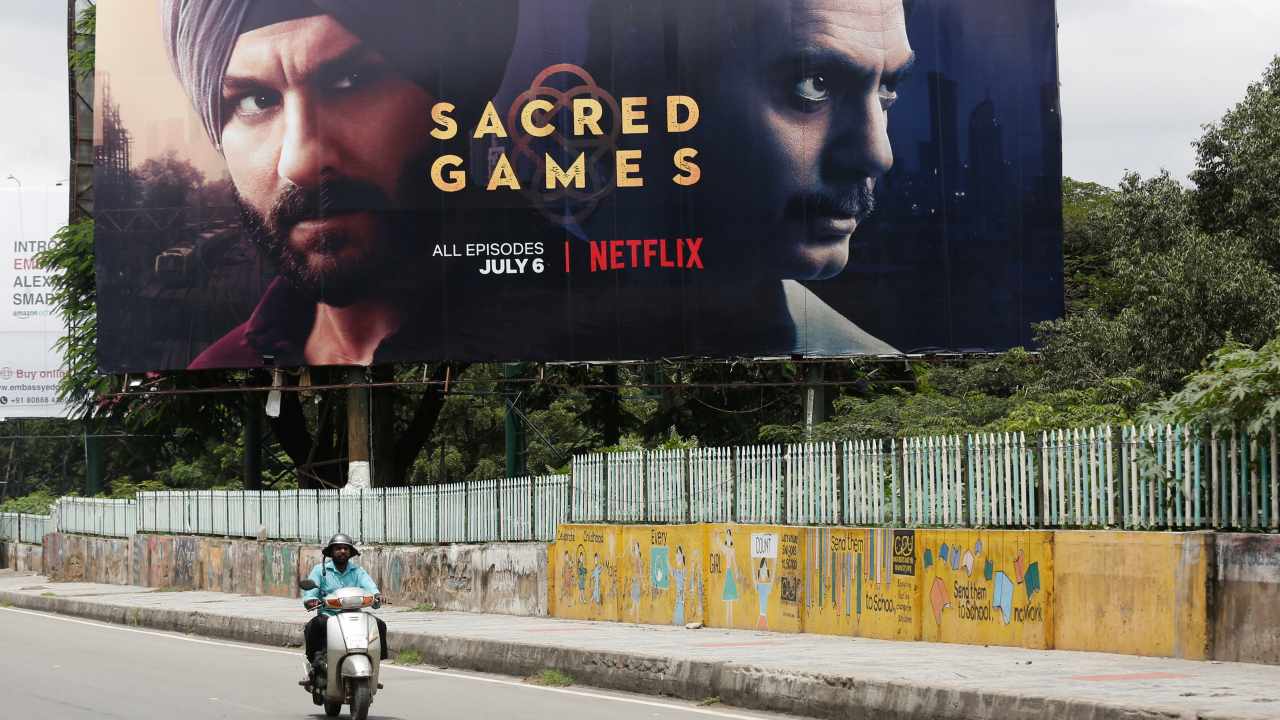 A man rides his scooter past a hoardings of Netflix's new television series