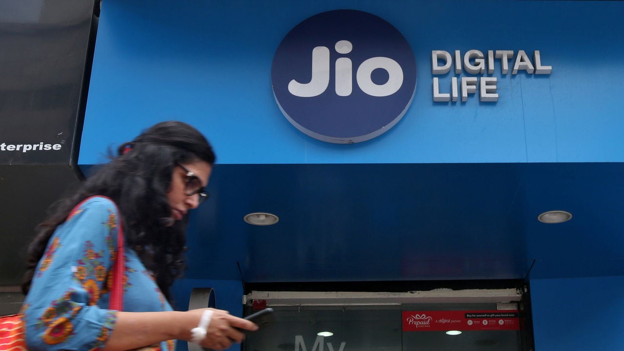 A woman checks her mobile phone as she walks past a Reliance Jio Store. Reuters