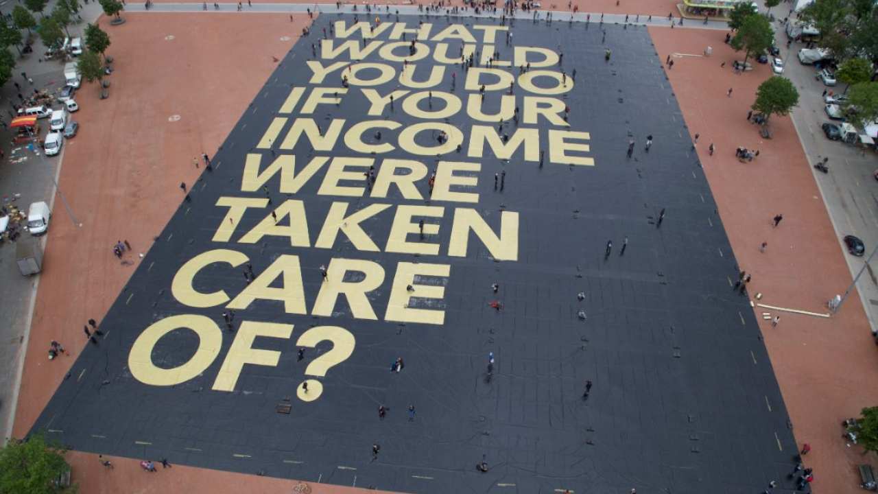 Activists for a universal basic income install a giant poster in a public square in Geneva, Switzerland, in 2016, ahead of a referendum on the issue, which failed. Image courtesy: University of Toronto.