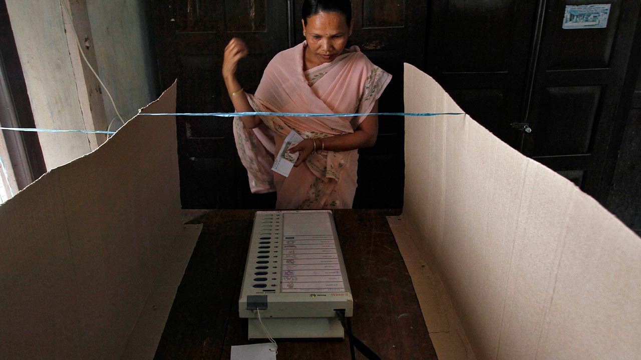 A woman prepares to cast her vote via EVM. Image: Reuters