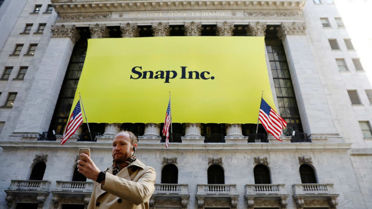 A man takes a photograph with a Snap logo hung in front of the New York Stock Exchange. Reuters