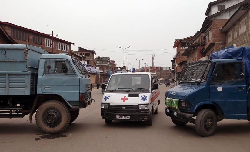 An ambulance moves between police vehicles parked to block a road during restrictions in downtown Srinagar. Reuters