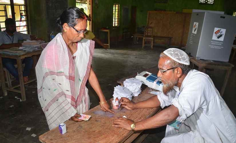 A polling officer puts indelible ink on a voter's finger at a polling booth in Nagaon, Assam. PTI