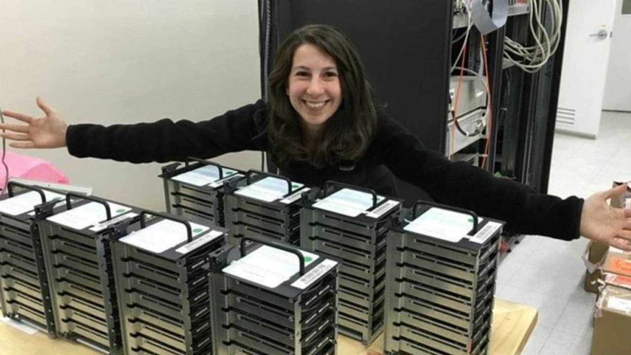 Astronomer Katie Bouman posing with the 5 petabytes of data needed for the black hole photo. Image: BBC