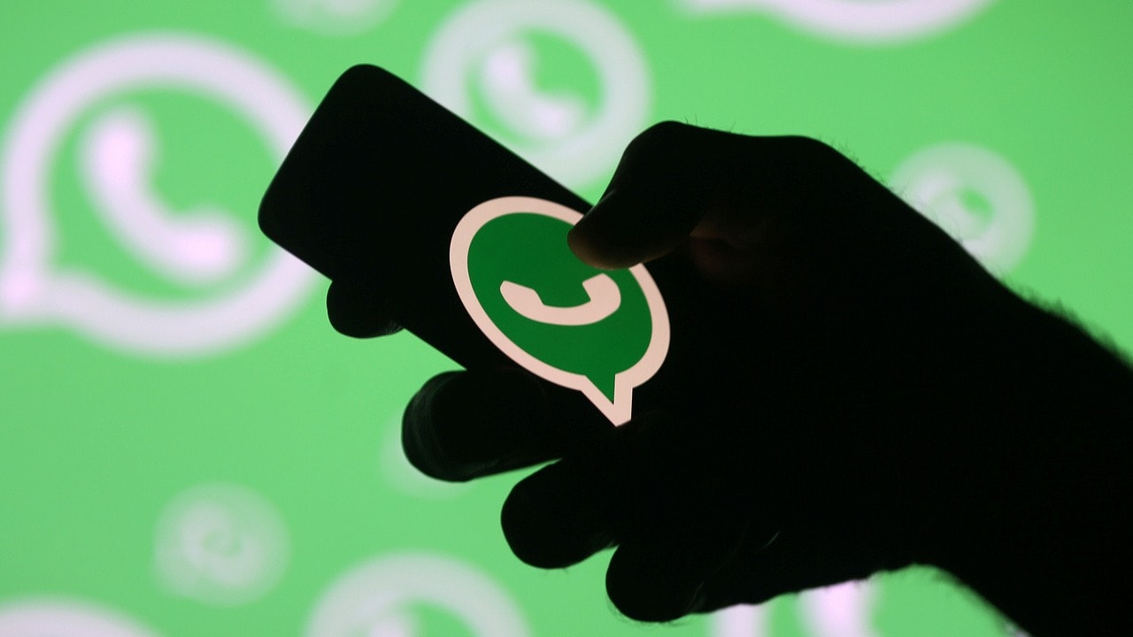 A man poses with a smartphone in front of displayed Whatsapp logo in this illustration September 14, 2017. Image: Reuters.
