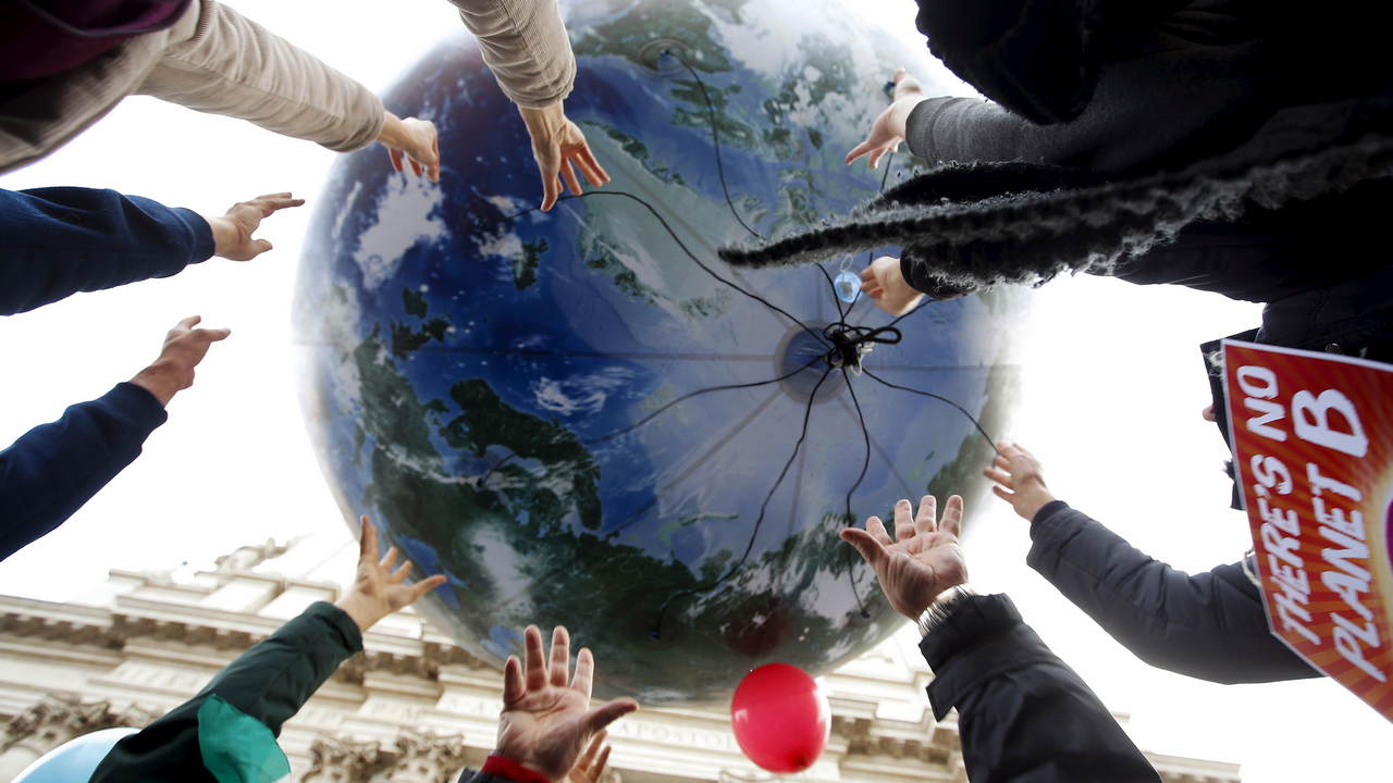 Protesters throw up a globe-shaped balloon during a rally held the day before the start of the COP21 summit. image credit:Reuters