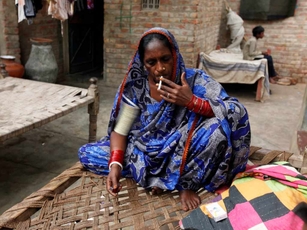 lalee Kolhi, a freed bonded labourer turned activist, smokes a cigarette while she sits on a bed at her home in Hyderabad. Image: Reuters