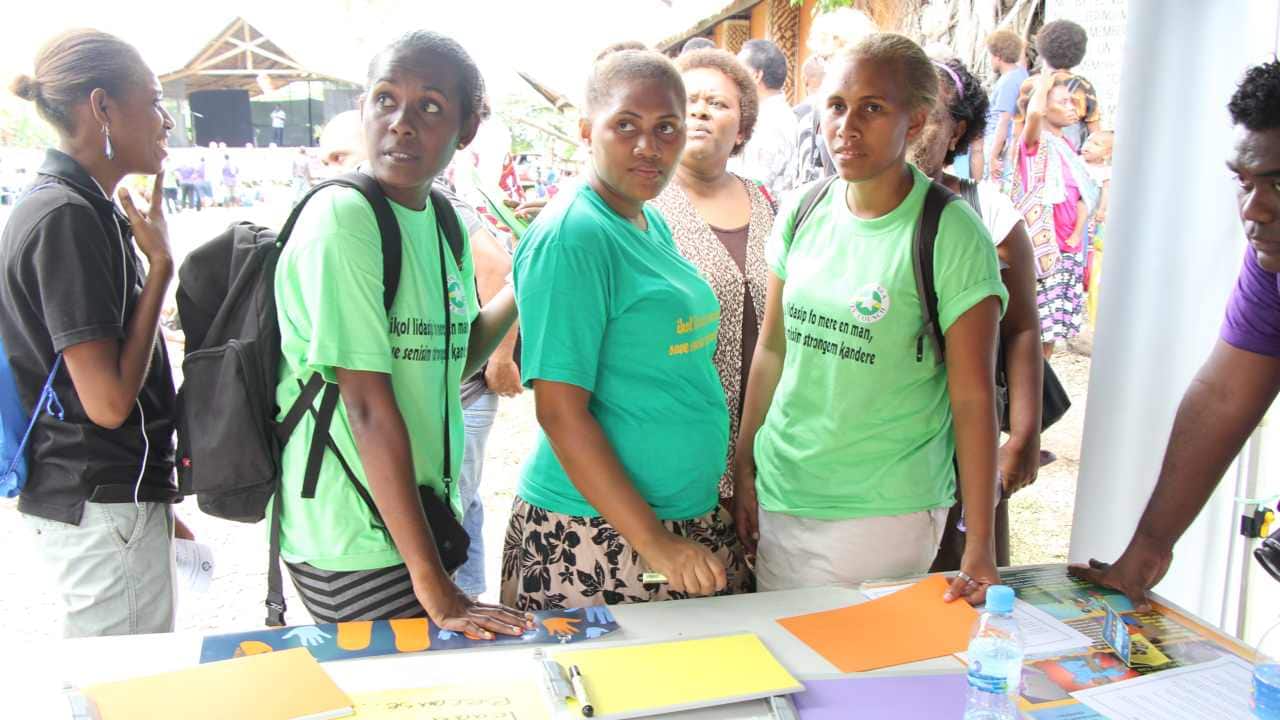 Visitors to the UN Women stall read through messages previous visitors have written. Image: UN Women/Marni Gilbert