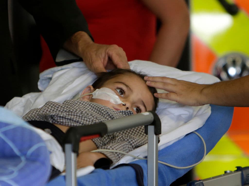 A 5-year old boy with a brain tumour, lies on a stretcher as he arrives with his parents. Reuters