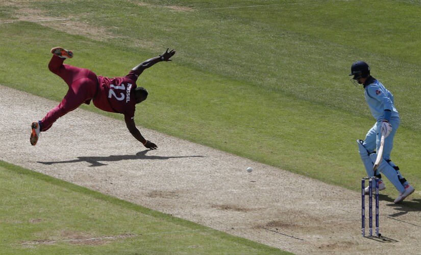 West Indies’ Andre Russell (L) is watched by England’s Joe Root as he attempts to field a ball off his own bowling during the 2019 Cricket World Cup group stage match between England and West Indies . AFP