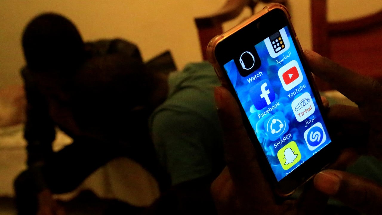 A Sudanese man holds his phone with restricted internet access social media platforms. Image: Reuters