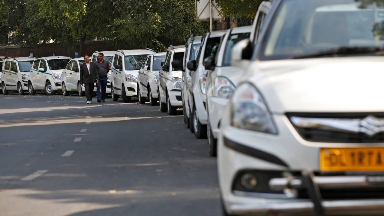 Drivers of Uber and Ola walk next to their parked vehicles. Reuters