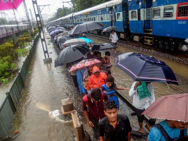 Commuters walk along flooded tracks during heavy Monsoon rains in Mumbai. PTI