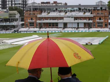 Two spectators sit in the stands and look out on the pitch which is covered as rain stops play on day three of the 2nd Ashes Test cricket match between England and Australia at Lord’s cricket ground in London, Friday, Aug. 16, 2019. (AP Photo/Alastair Grant)
