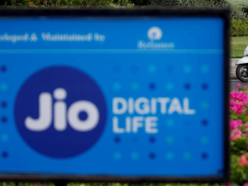 A woman rides her scooter past advertisements of Reliance Industries' Jio telecoms unit, in Ahmedabad, India, July 5, 2018. REUTERS/Amit Dave - RC1B8DB7B2E0