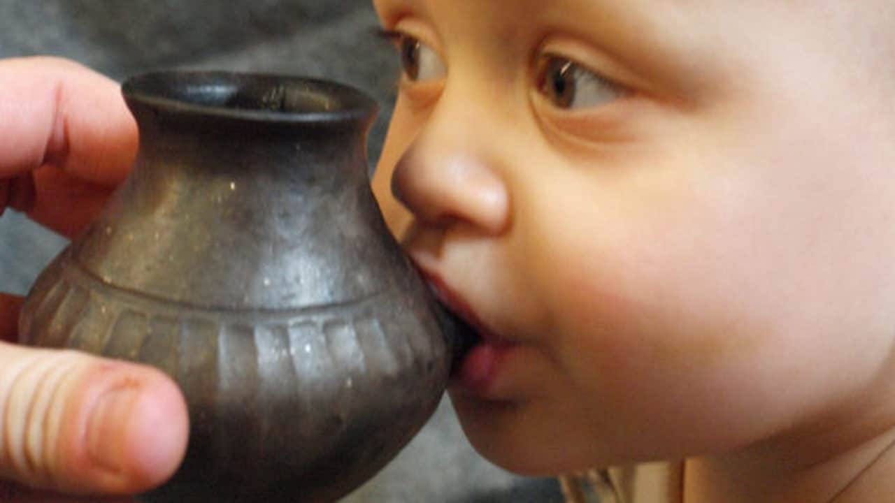 A baby tries out a replica feeding vessel similar to ancient ones now reported to contain chemical remnants of nonhuman animal milk. image credit: HELENA SEIDL DA FONSECA 