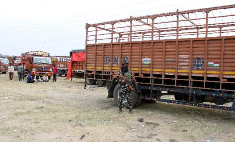 A security personnel stands guard near out-of-state truckers in Shopian, Kashmir. Image courtesy: Nisar Ul Haq