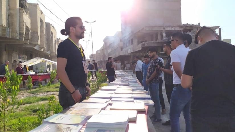 Resident of Mosul browse through books on Al Najafi Street. Image via Facebook/ UNESCO Iraq