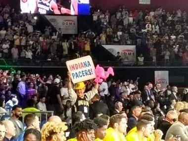 Matt Asen, or The Pacer Guy, holds up a banner and a pink flamingo during the NBA India Games on Saturday. Image: Amit Kamath