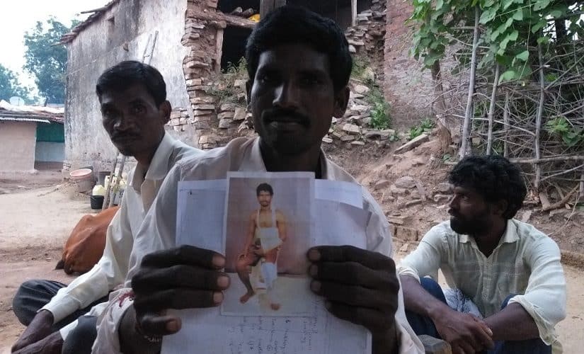 Maruti Aiyya Atram, holds up a picture from when he was injured after forest department officials lathi-charged locals. Firstpost/Natasha Trivedi