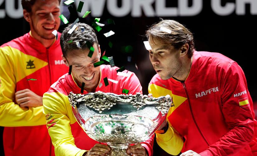 Spain's Roberto Bautista Agut holds the Davis Cup trophy while teammate Rafael Nadal blows confetti off it after Spain defeated Canada 2-0 to win the final in Madrid. AP