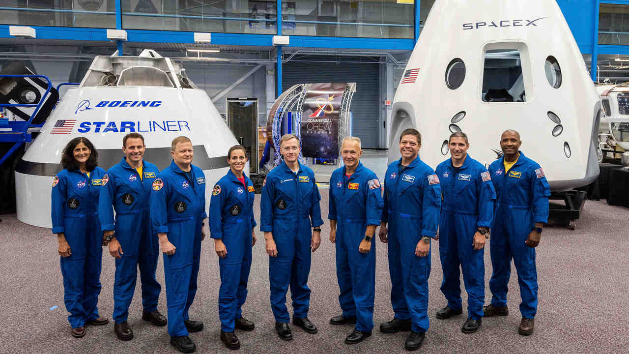 Astronauts standing in front of mockups of Boeing's CST-100 Starliner and SpaceX's Crew Dragon capsules at the Johnson Space Center in Texas. Image credit: NASA/AP