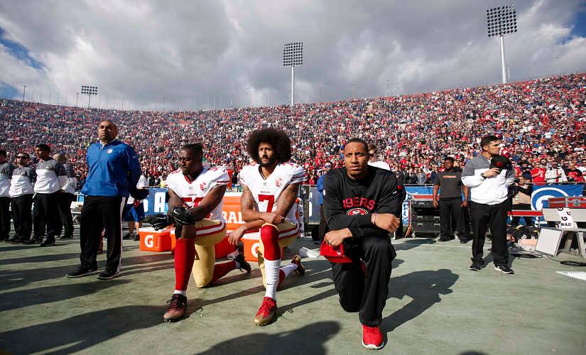 Colin Kaepernick (centre) kneels along with two other San Francisco 49ers teammates during the national anthem in December 2016. Getty Images